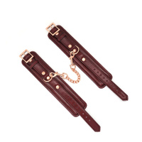 Szykowne kajdanki na ręce z licowej ścisłej skóry bydlęcej w kolorze burgundowym z okuciami i łańcuchem z metalu w kolorze złota